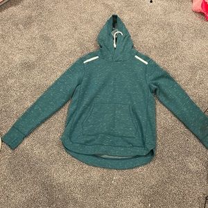 A greenish blue large sweatshirt with some white patterns.